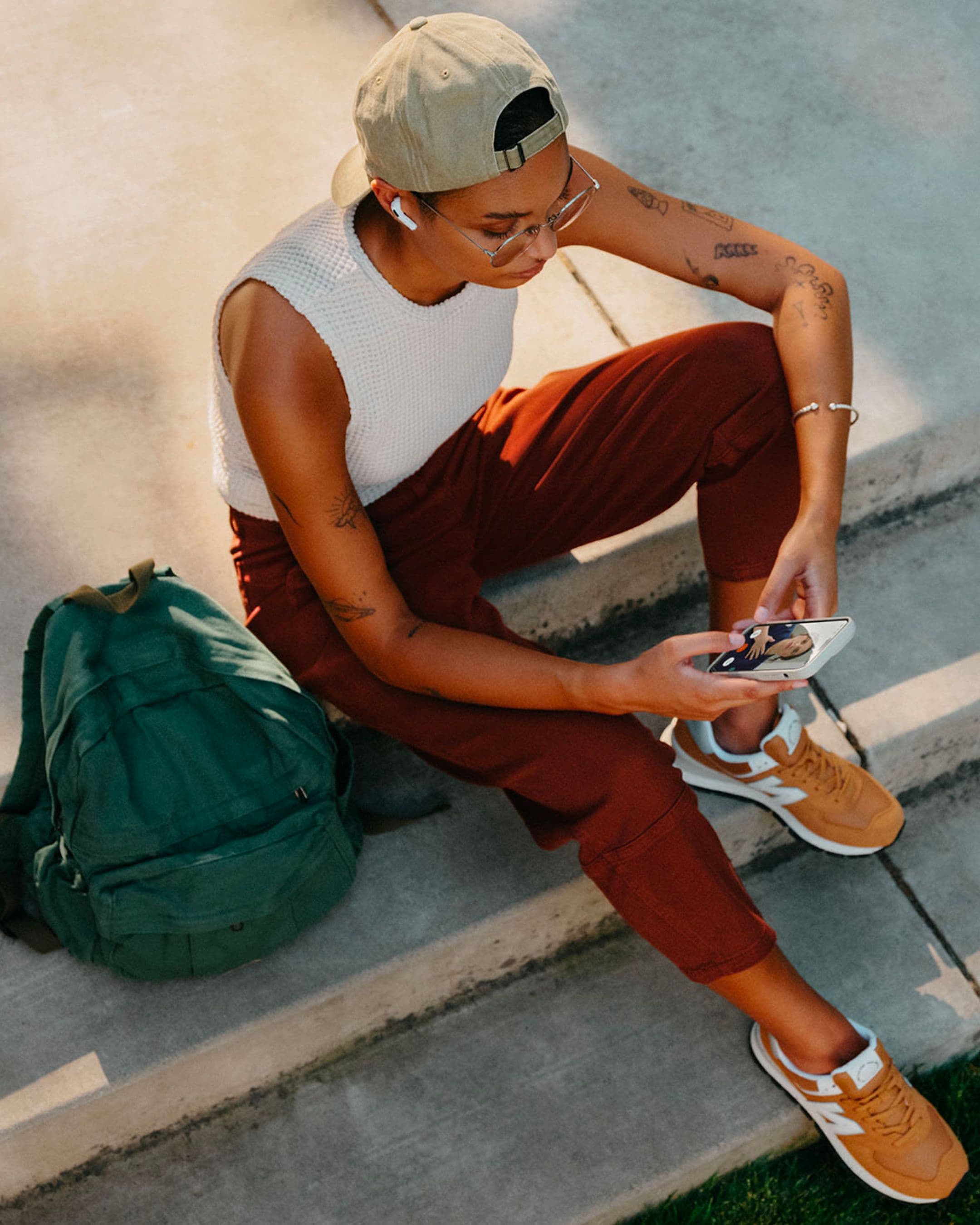 A person sits on concrete steps video-calling a medical professional via Amazon medical.
