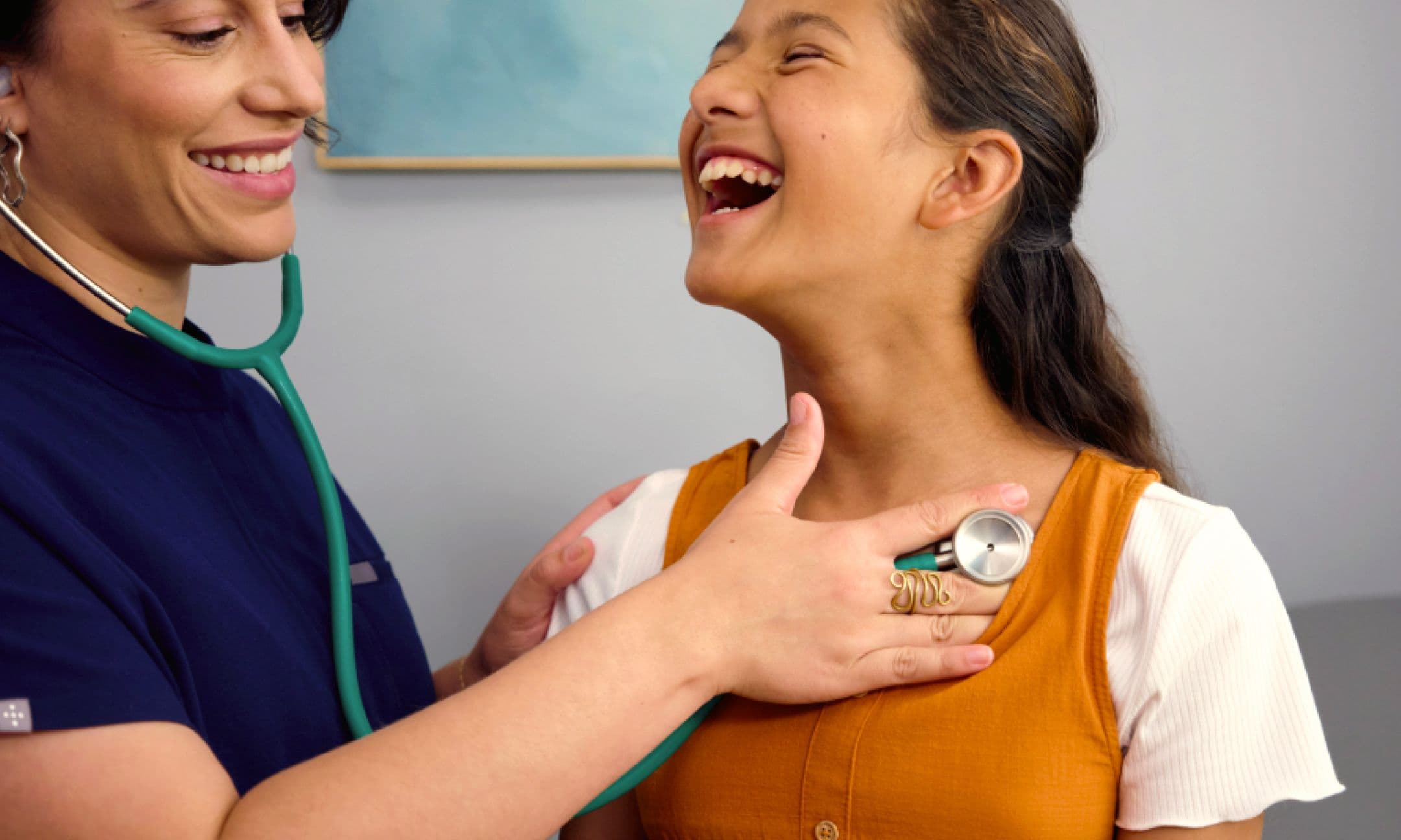 An Amazon healthcare professional in navy scrubs uses a stethoscope to listen to a girl’s chest.