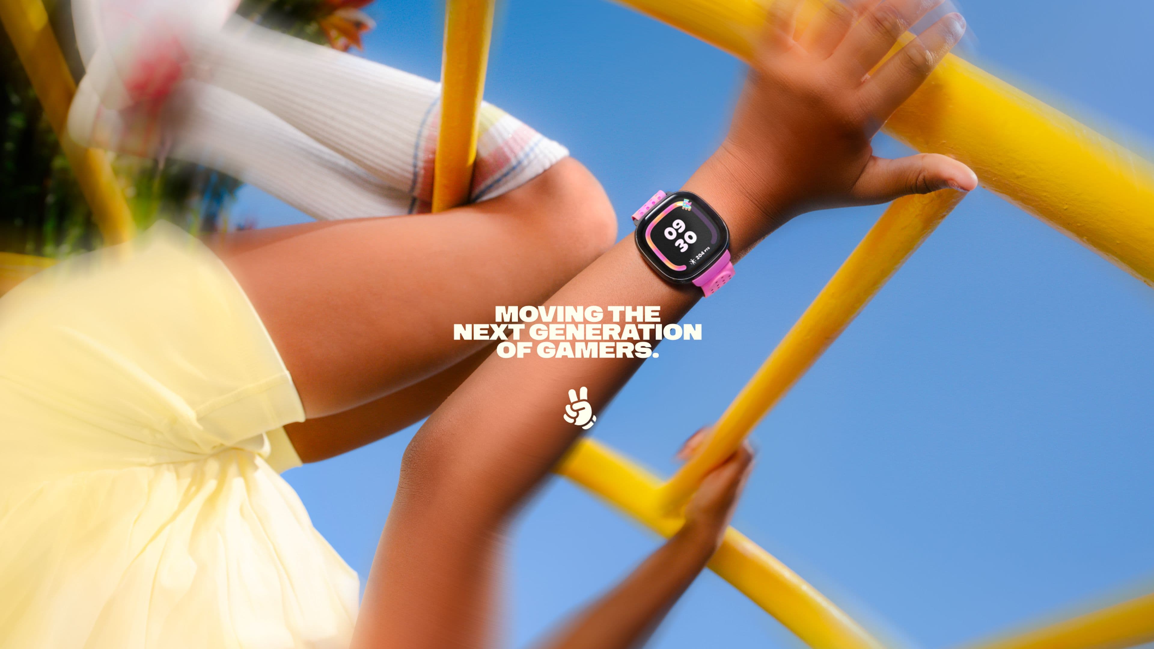 Child in yellow dress wearing a Fitbit Ace climbs yellow playground bars, with text: 'MOVING THE NEXT GENERATION OF GAMERS.'