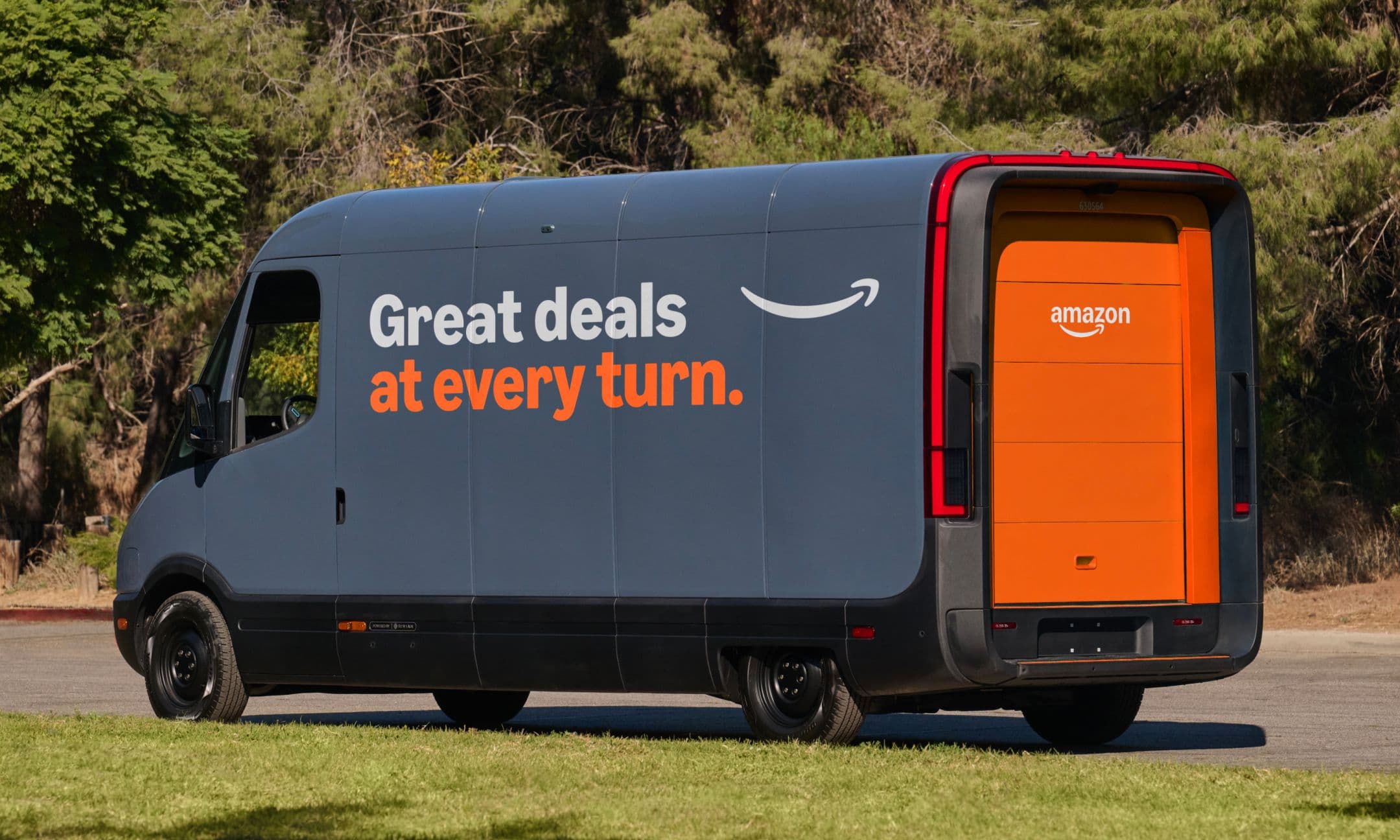 A dark gray Amazon delivery van with orange accents is parked on a road.