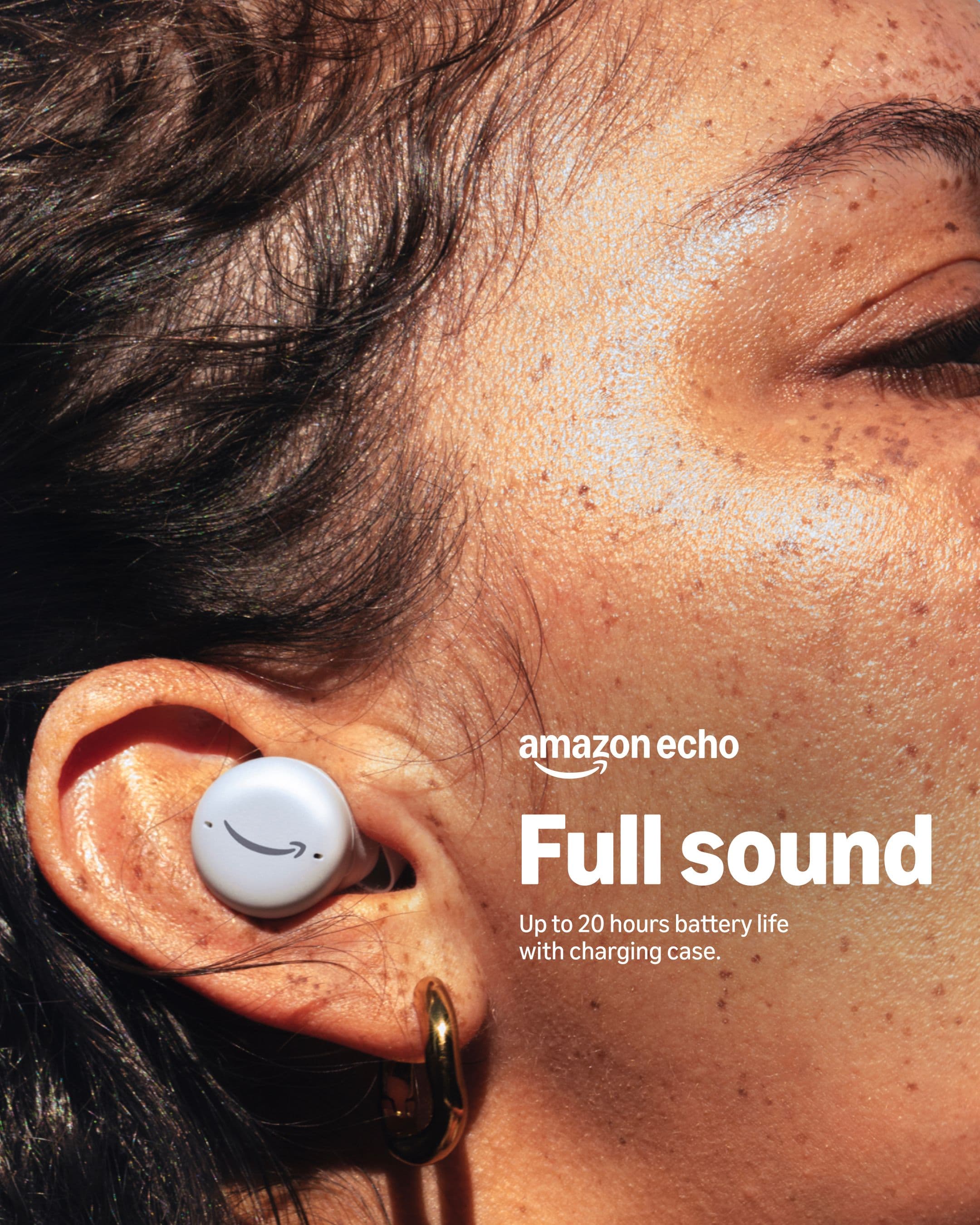 Close-up of a person’s ear wearing a white Amazon Echo earbud with the Amazon logo. Text reads: amazon echo Full sound. Up to 20 hours battery life with charging case.
