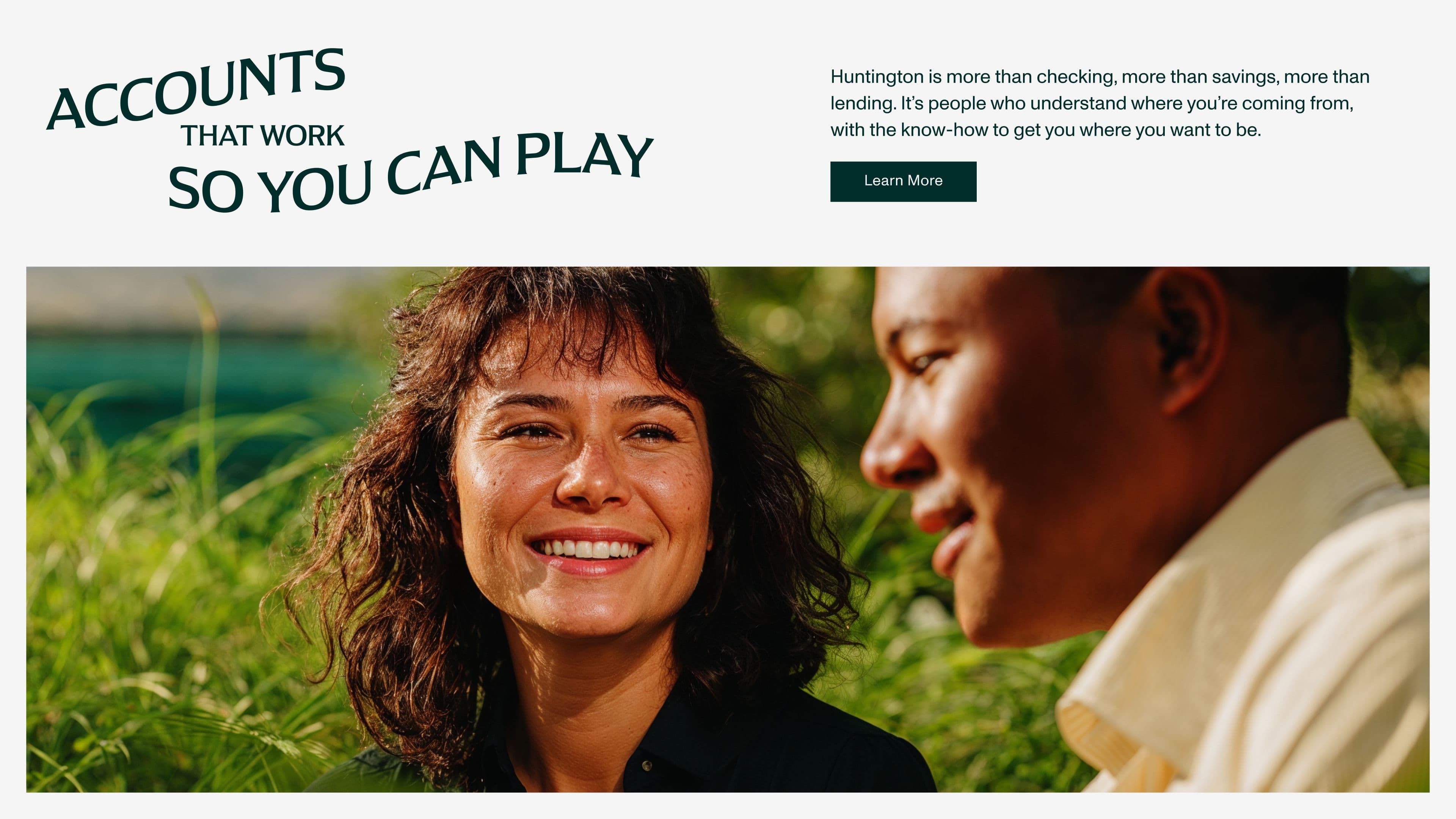 Two people sit outside smiling and talking in a grassy area. Stylized text reads, Accounts that work so you can play.