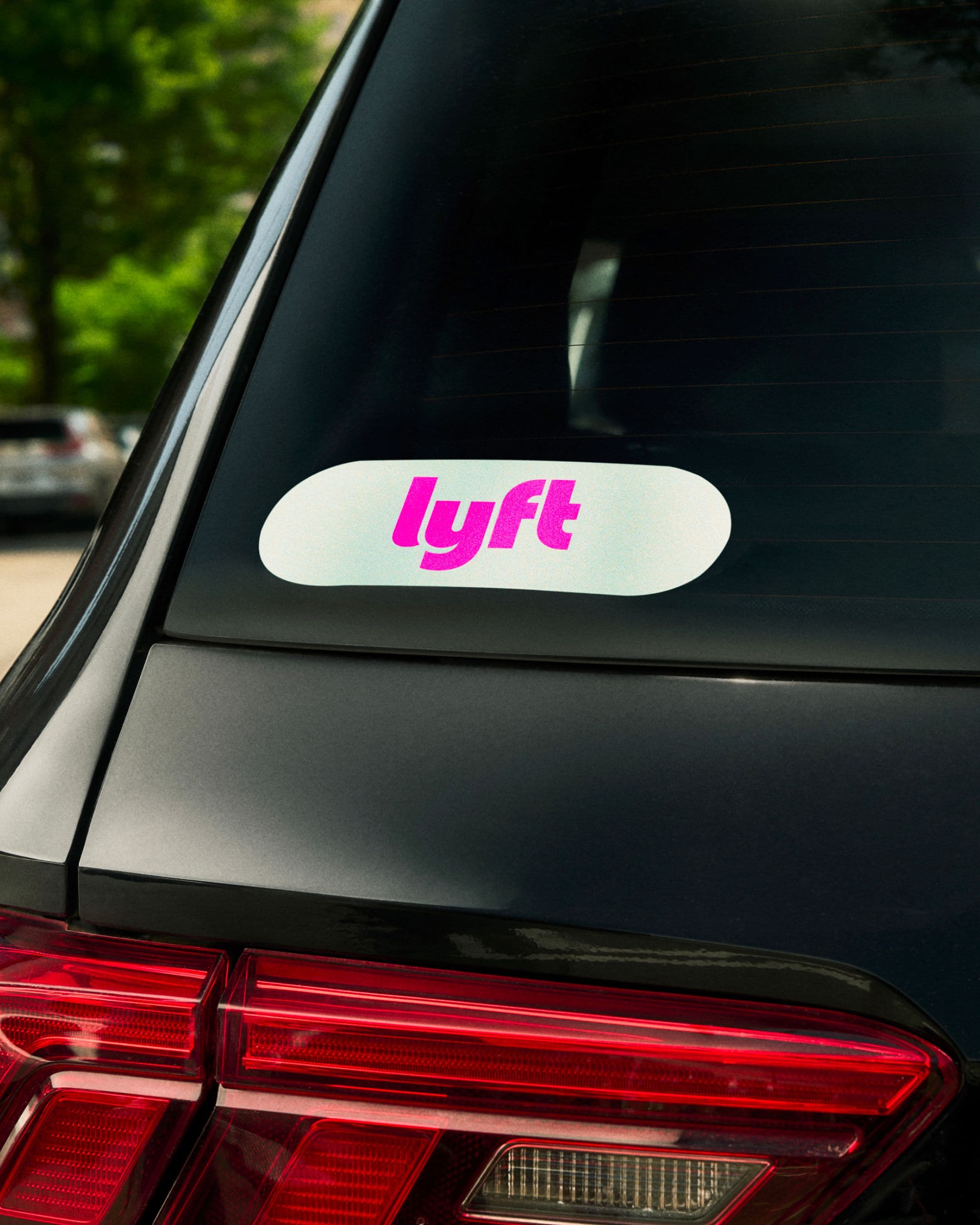 A Lyft sticker is displayed on the rear window of a black car.
