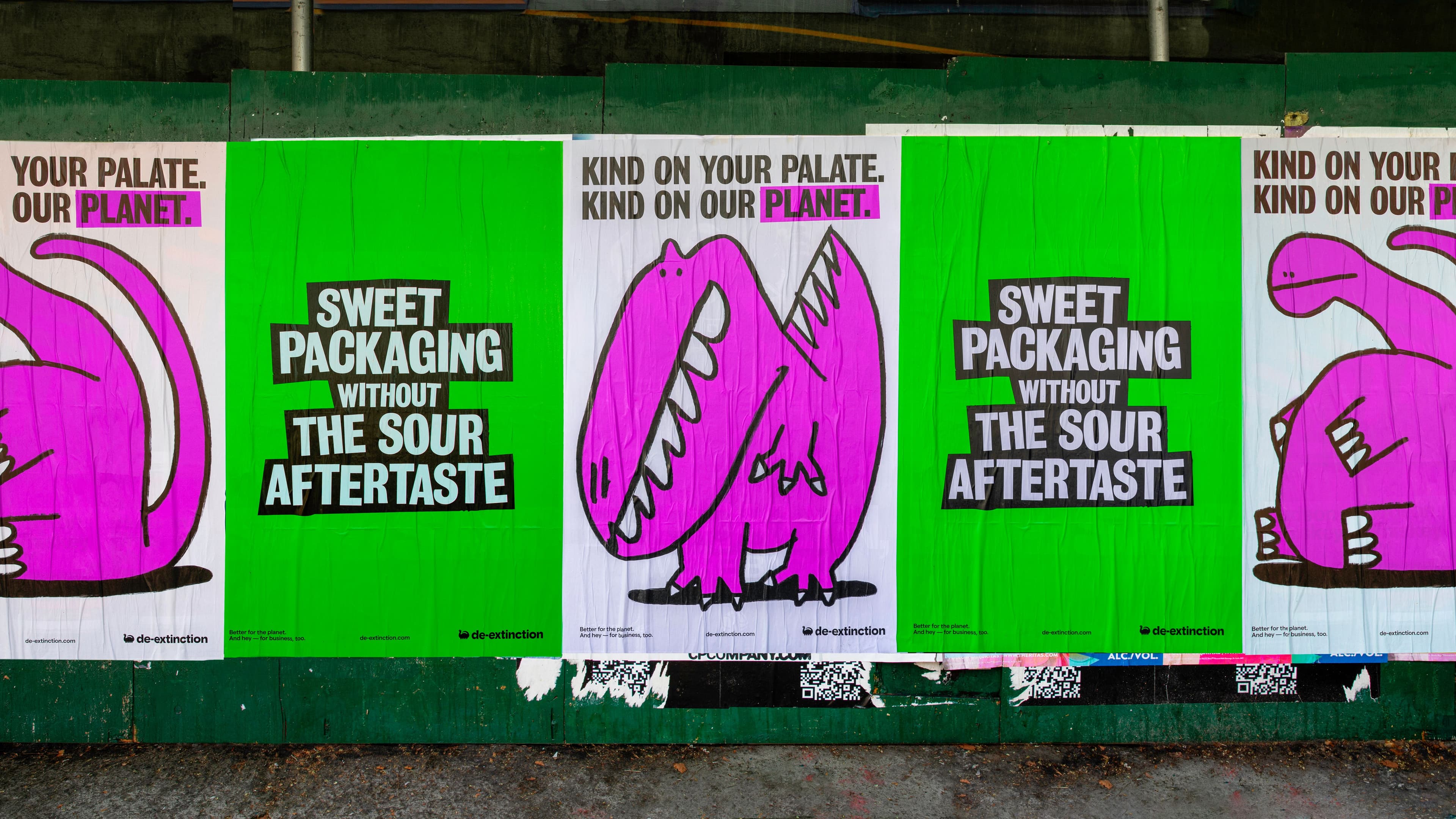 A series posters for "de-extinction" featuring a chunky pink cartoon dinosaur and bold typography. The posters the phrases "Sweet packaging without the sour aftertaste" and "Kind on your palate. Kind on our planet.”