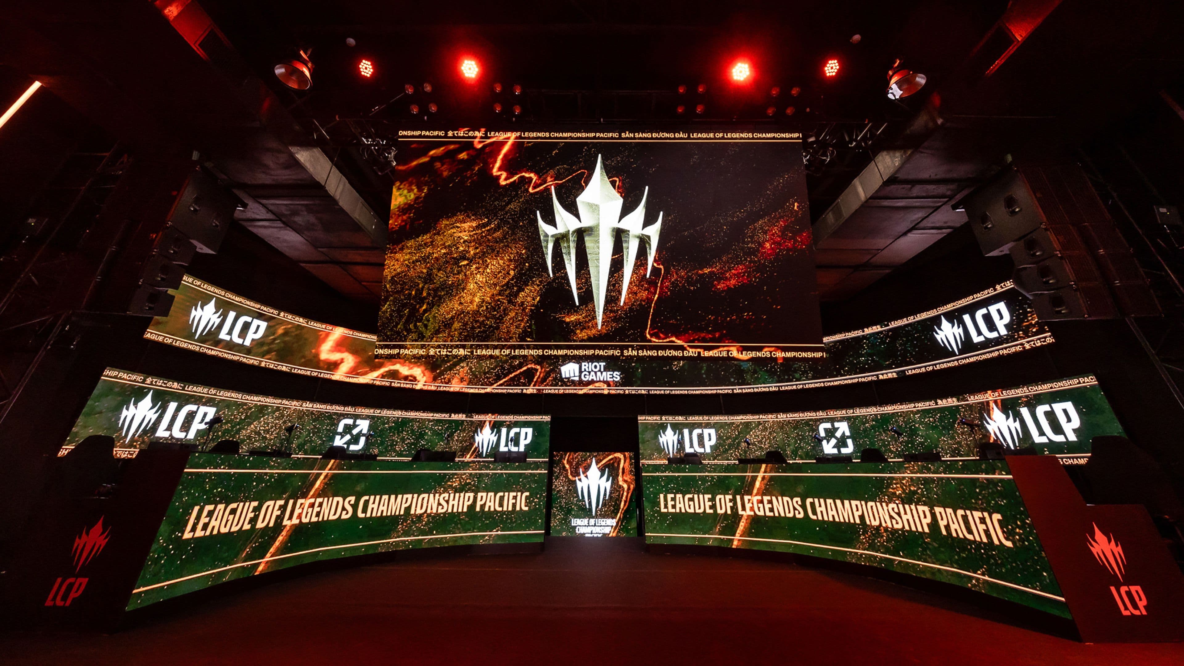 A brightly lit esports stage displays multiple screens with League of Legends Championship Pacific and the LCP logo, featuring bold graphics and dramatic lighting.