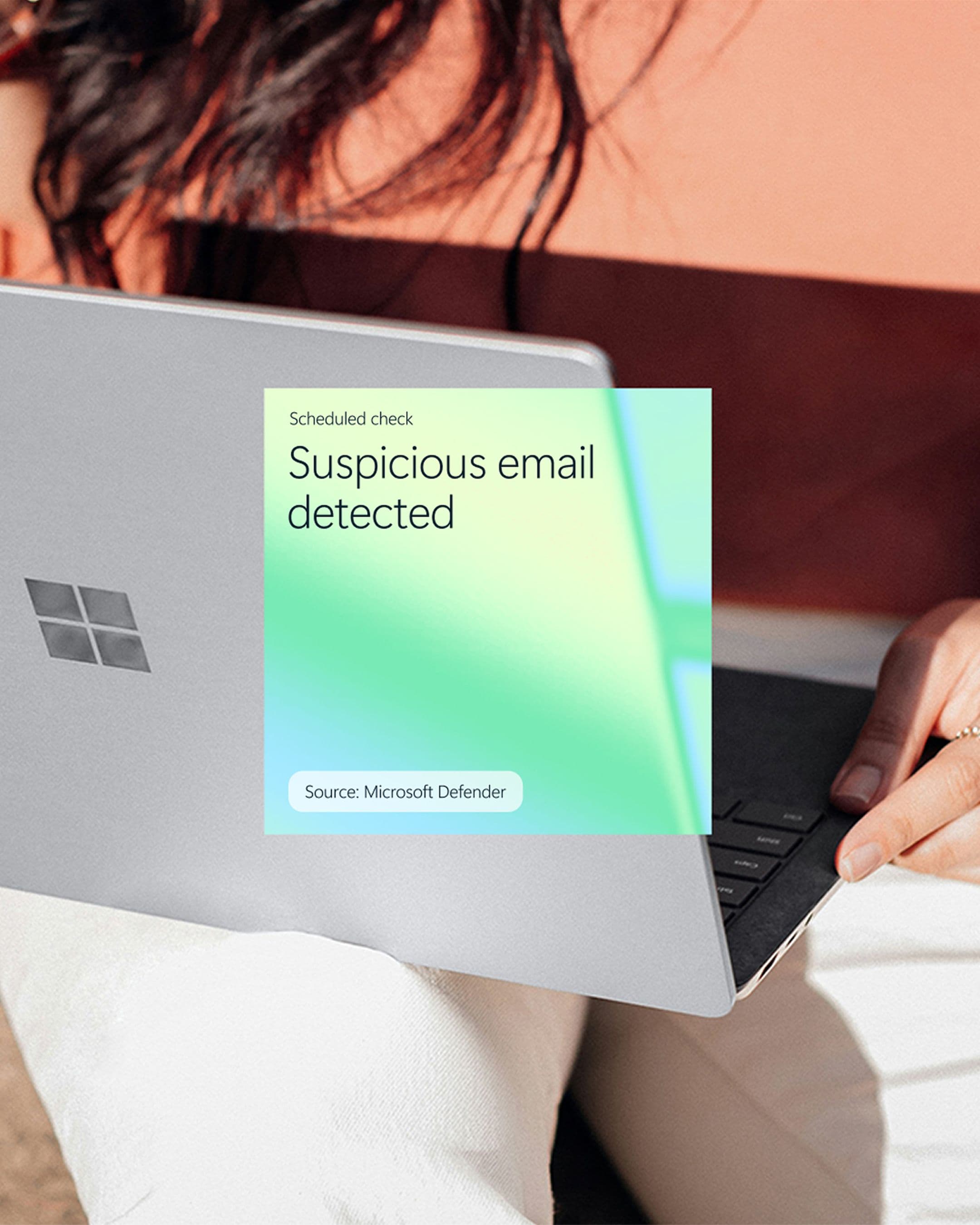 Laptop showing Microsoft Defender alert on a scheduled check: “Suspicious email detected.”