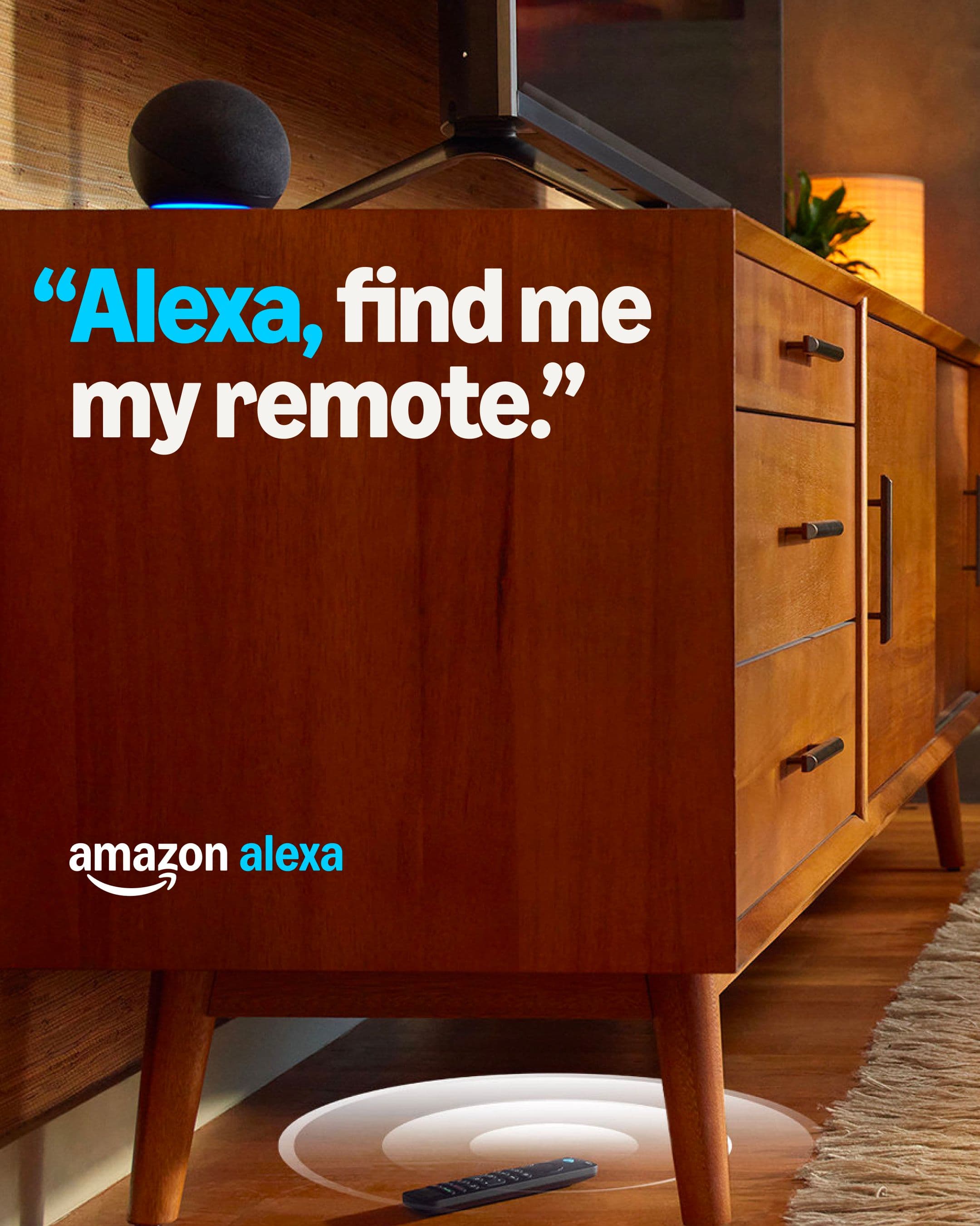 TV remote on the floor under a cabinet, glowing circle shows its location; text above says ‘Alexa, find me my remote.'