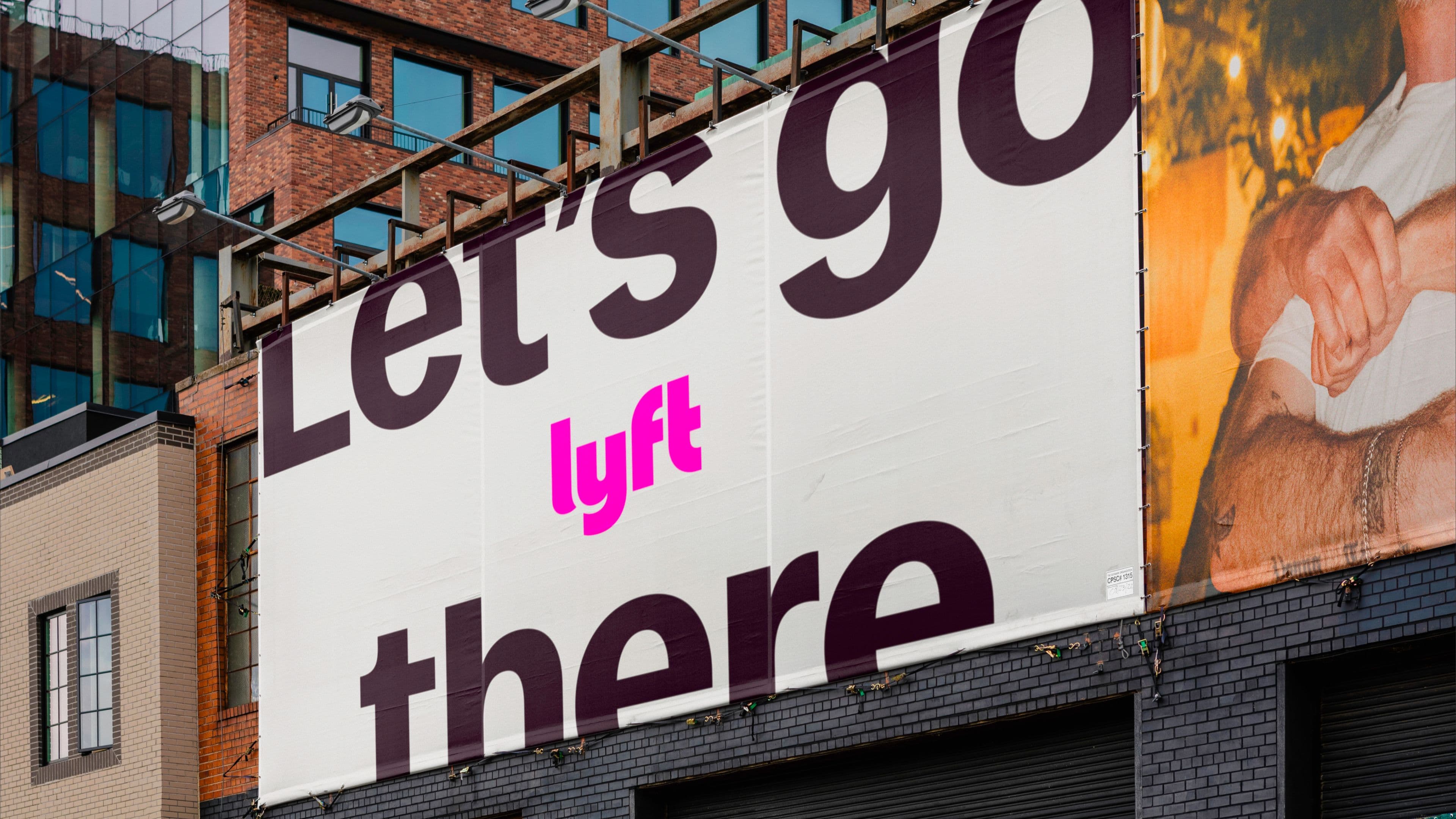 Large outdoor billboard on a city building reading ‘Let’s go there’ with the pink Lyft logo in the center.