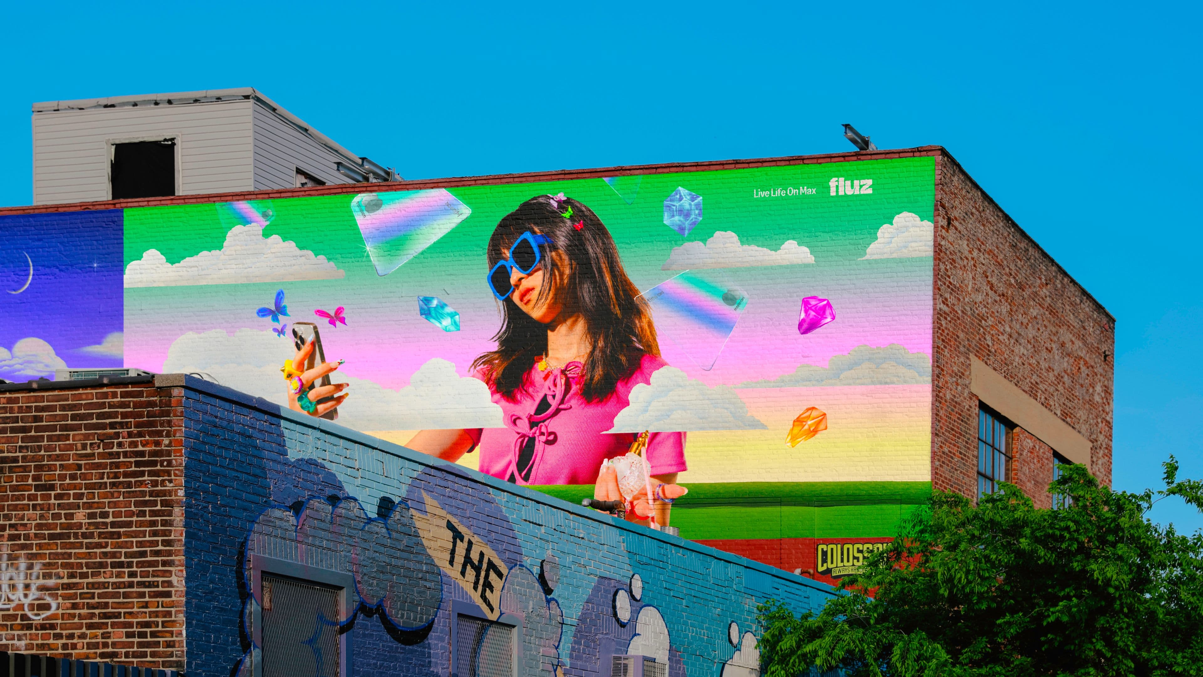 Colorful Fluz mural of a smiling girl in sunglasses holding a phone.