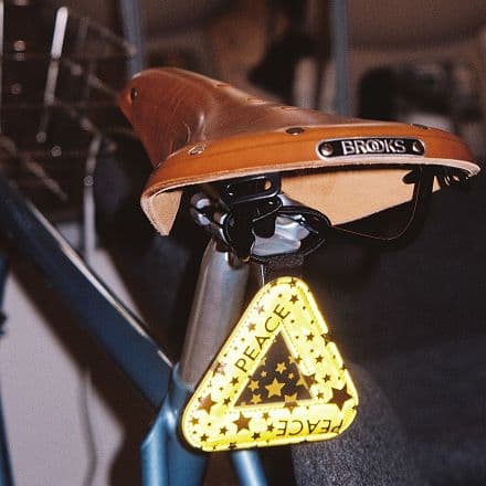 Close-up of a brown Brooks bicycle saddle with a yellow peace-sign keychain.